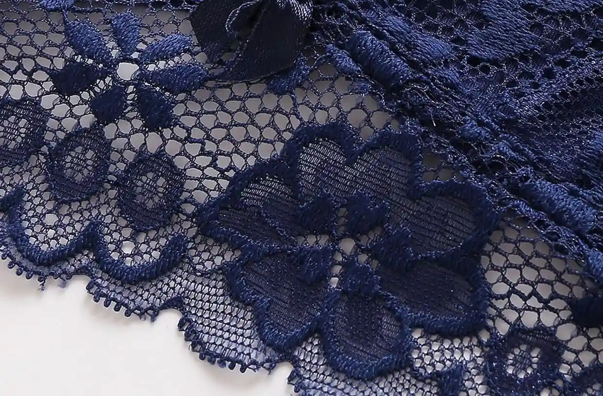Close - up of soft, navy blue lace with intricate floral patterns and scalloped edges