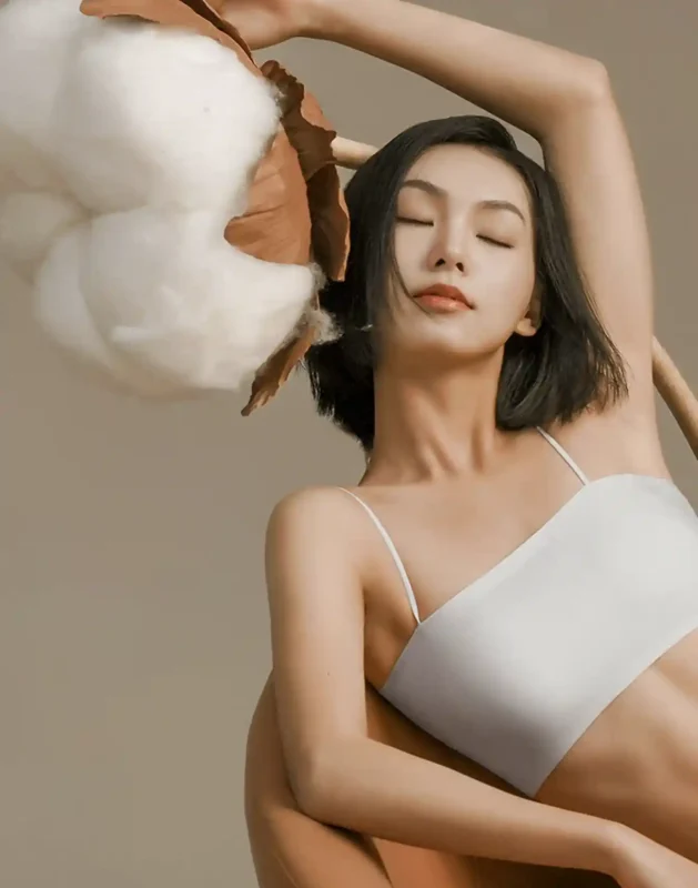 Private Label Lingerie Suppliers02 zoralinkcom A person wearing a light colored lingerie bra with a large cotton boll beside them showcasing comfort and natural materials offered by lingerie suppliers with custom lingerie service
