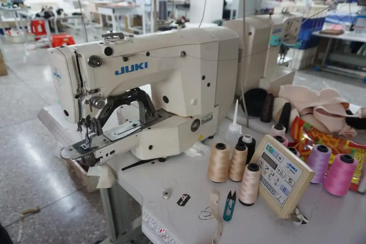 A Juki sewing machine in a workshop surrounded by colorful thread spools and sewing tools